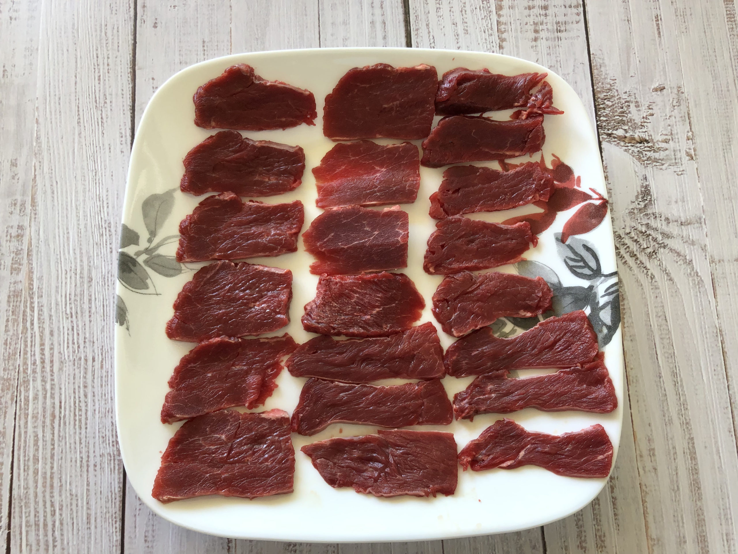 raw thin sliced bison meat on a plate
